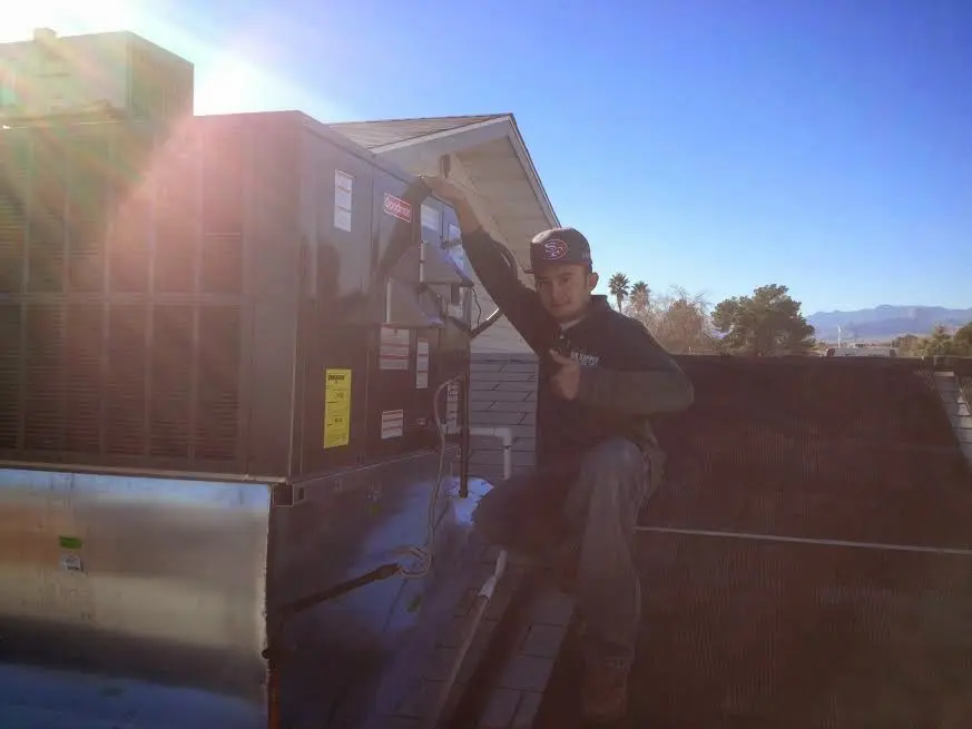 HVAC technician performing Air Duct Cleaning on a rooftop unit in Lynchburg