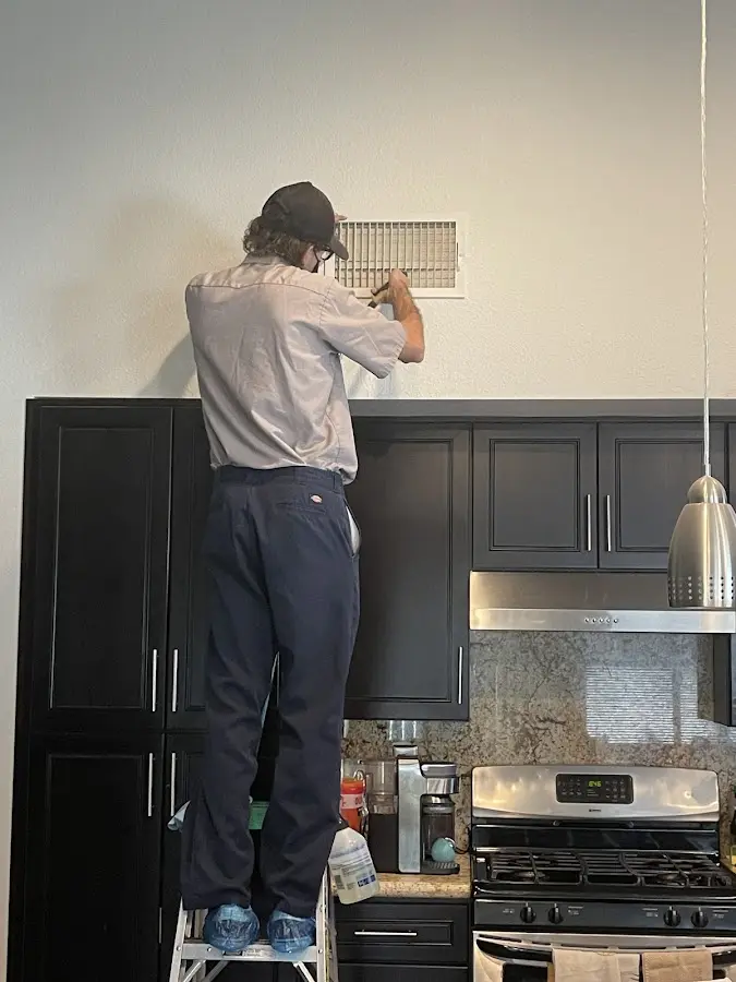 Technician inspecting an air vent during HVAC service in Lynchburg